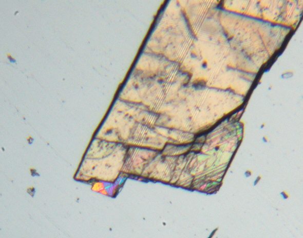 [ small calcite crystal showing typical intererence colours ]
